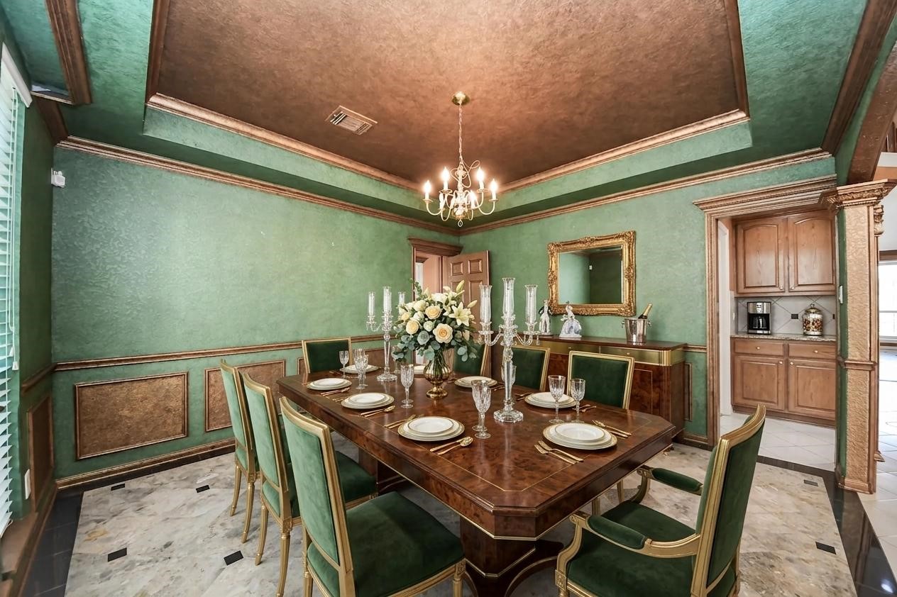 20111 Biscayne Hill Court Spring, TX 77379 - Photo 7 of 44 Elegant dining room with a rich green and gold color scheme. Features a large wooden table set for eight, a classic chandelier, and decorative wainscoting.