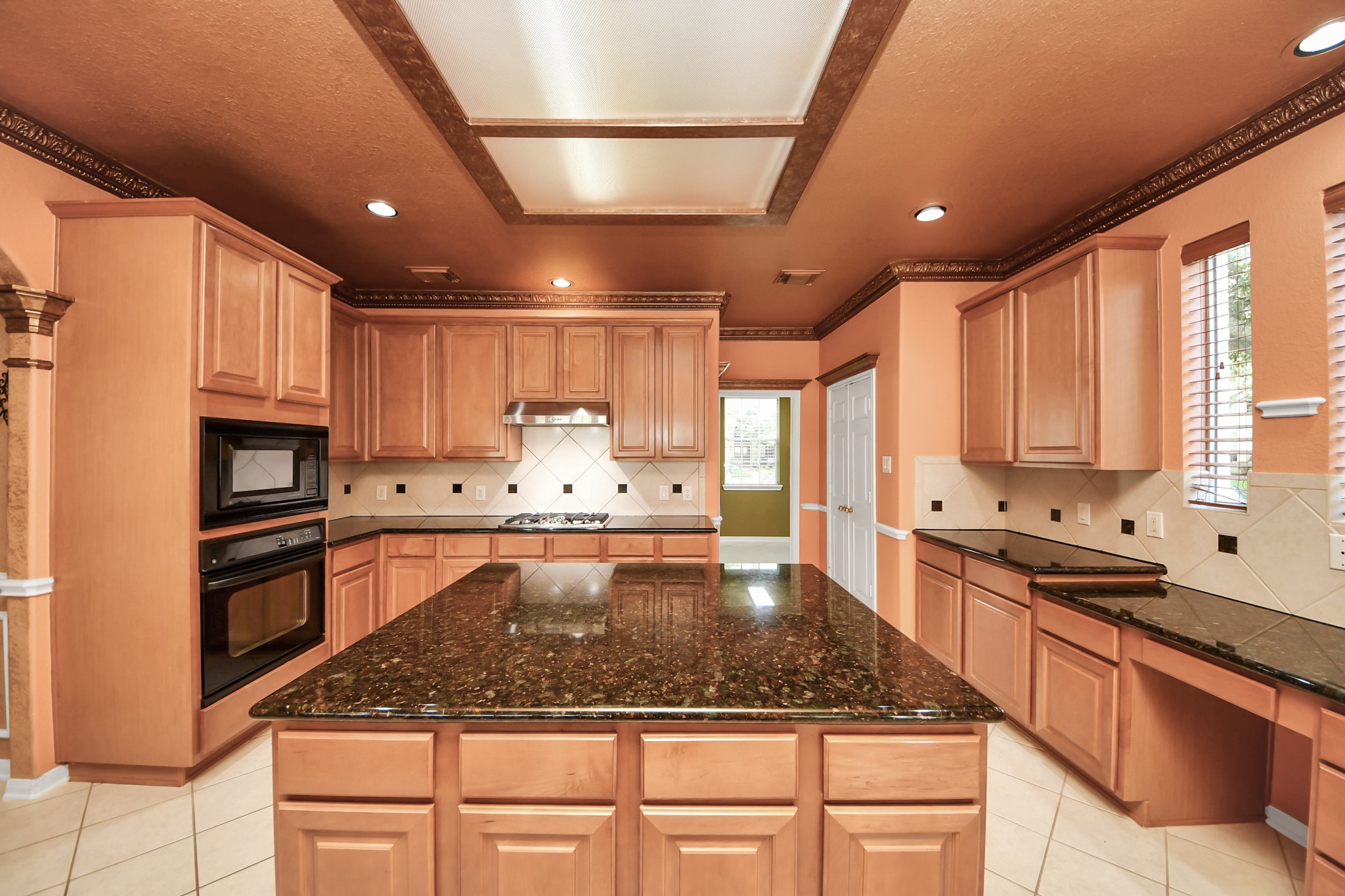 20111 Biscayne Hill Court Spring, TX 77379 - Photo 9 of 44 This kitchen features ample wooden cabinetry, granite countertops, and a large central island. It includes built-in appliances, a tiled backsplash, and recessed lighting, creating a warm and functional space for cooking and entertaining.