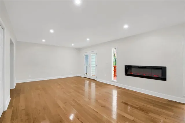 a view of an empty room with wooden floor and a fireplace