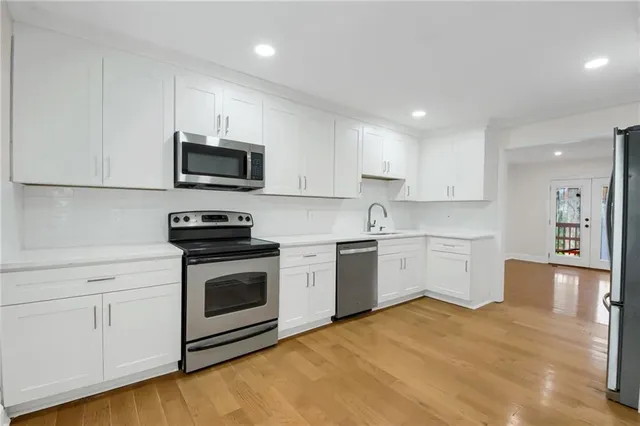 a kitchen with granite countertop white cabinets stainless steel appliances and a sink