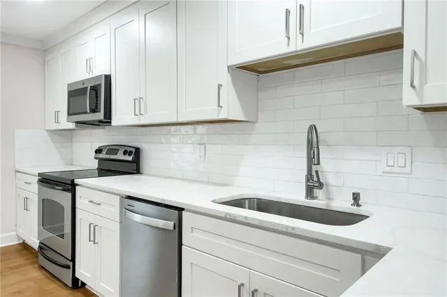 a kitchen with white cabinets a sink and white appliances