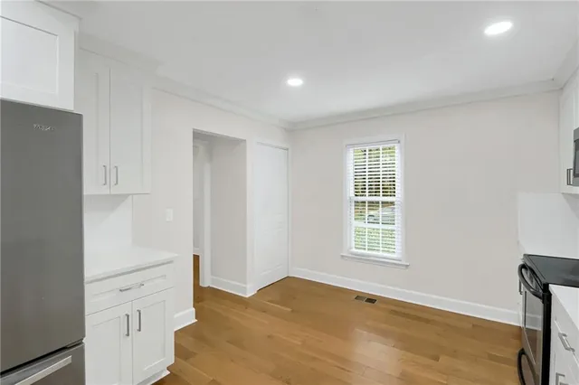 a view of an empty room with a window and wooden floor