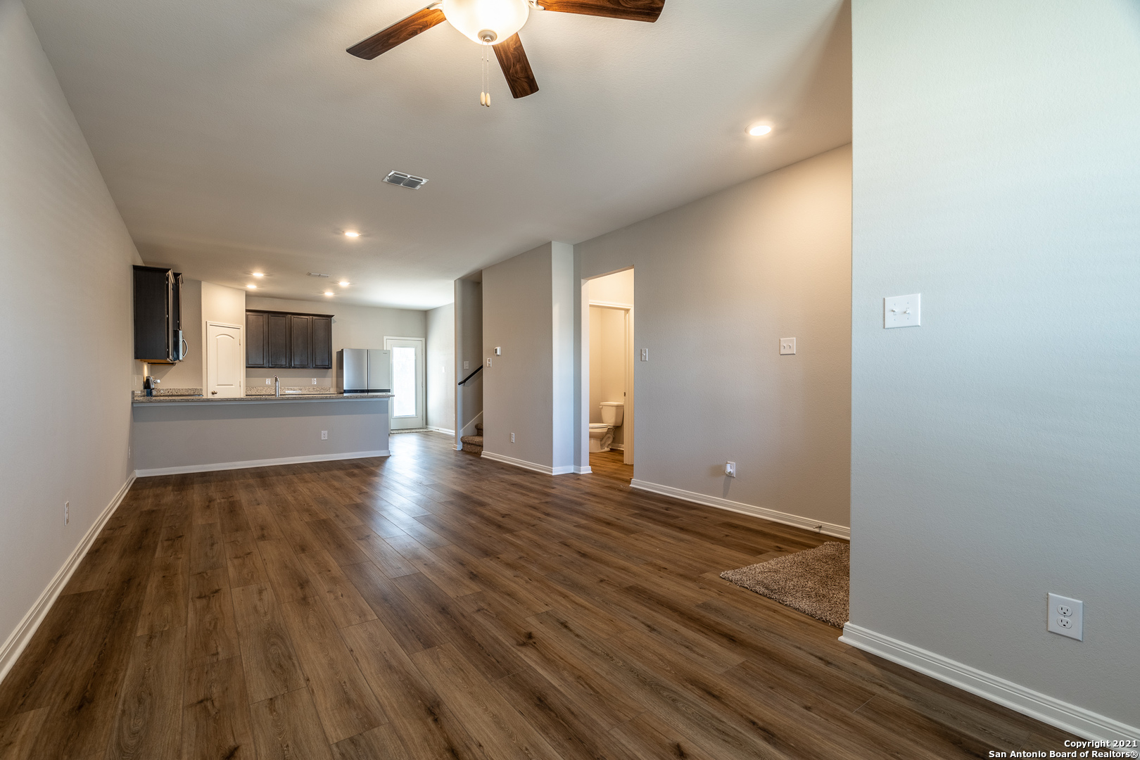 9338 Espadrille Run Converse, TX 78109 - Photo 8 of 46 an empty room with wooden floor chandelier fan and windows