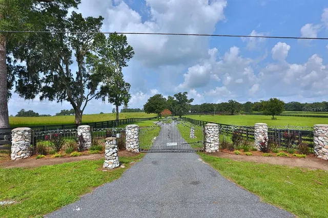 an aerial view of a residential houses with outdoor space and trees all around