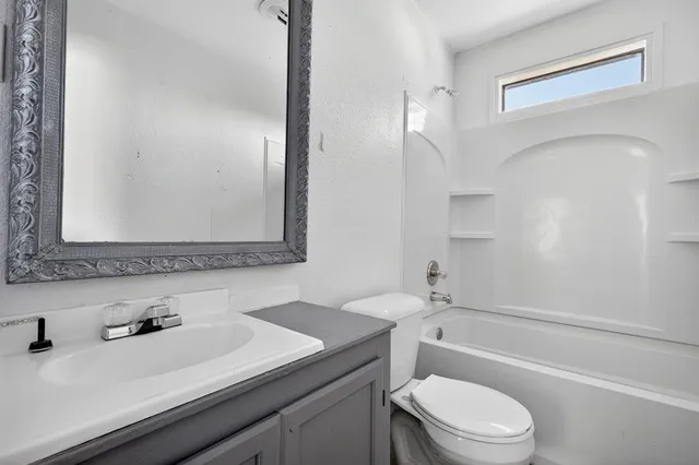a bathroom with a granite countertop sink toilet a mirror and shower