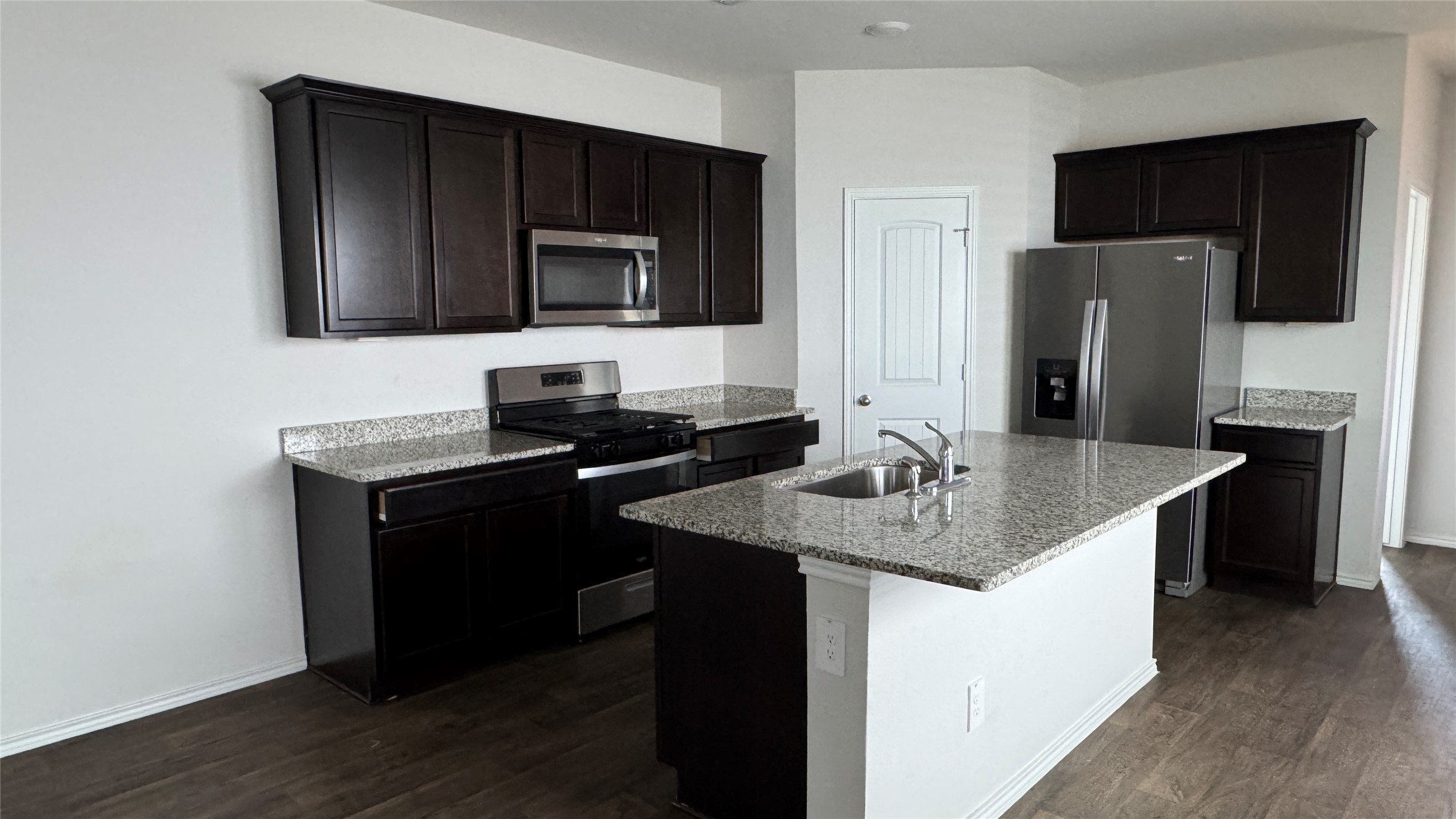 408 Frogmore Loop Kyle, TX 78640 - Photo 4 of 32 A well-appointed kitchen showcasing dark cabinetry, granite countertops, and modern appliances.