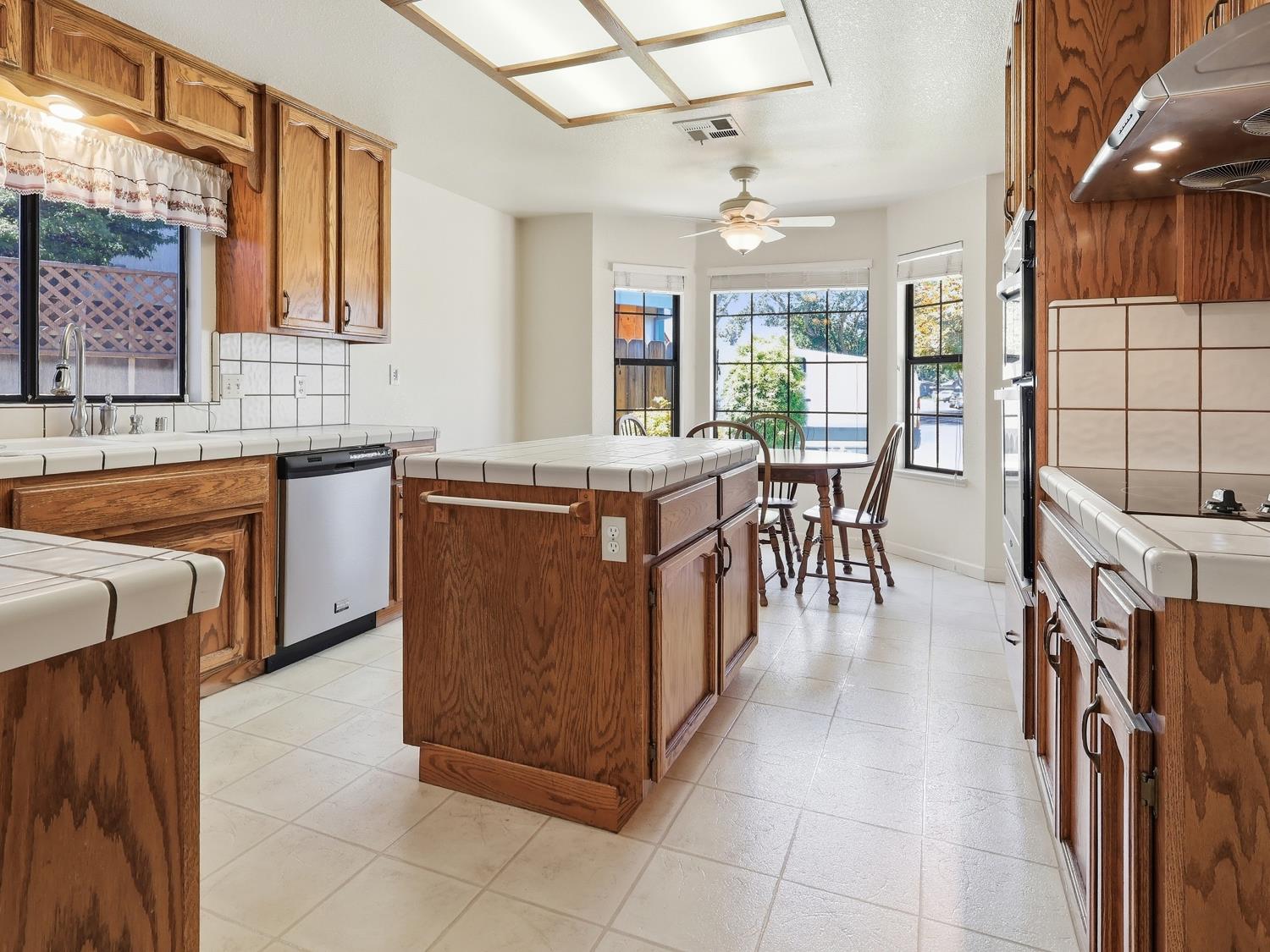 900 Multnomah Drive Modesto, CA 95350 - Photo 8 of 34 Kitchen featuring wood cabinetry, white tile countertops, a center island, and integrated stainless steel appliances