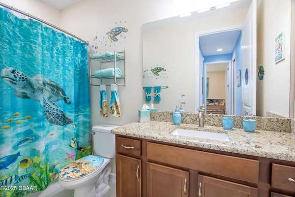 a bathroom with a granite countertop sink a toilet and a mirror