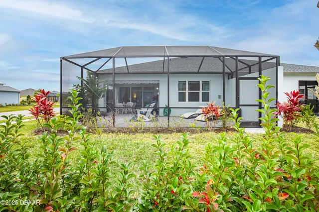 a view of a house with a big yard potted plants and palm trees
