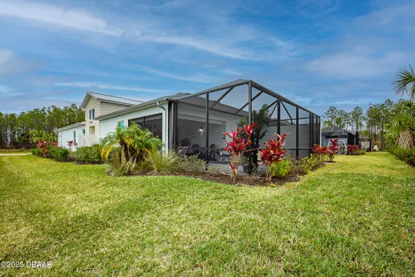 a view of a house with a big yard potted plants and palm trees