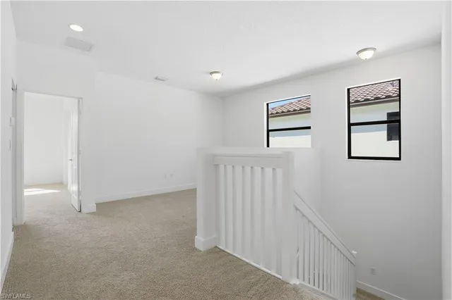 an empty room with chandelier fan and windows