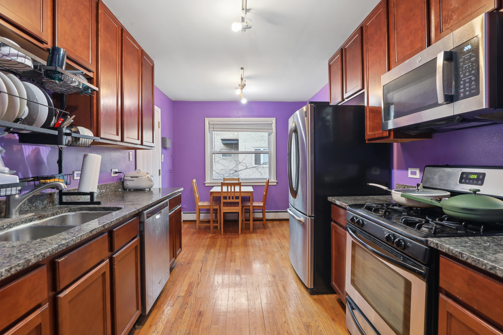 2147 Ridge Avenue, Unit 2D Evanston, IL 60201 - Photo 8 of 22 a kitchen with stainless steel appliances granite countertop a stove top oven a sink dishwasher a refrigerator and a dining table with wooden floor