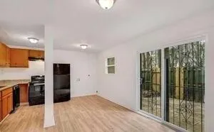 a view of a kitchen with a refrigerator a stove top oven wooden floor and a sink