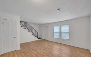 a view of empty room with stairs and wooden floor