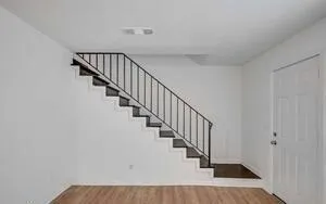 a view of staircase with wooden floor and white walls