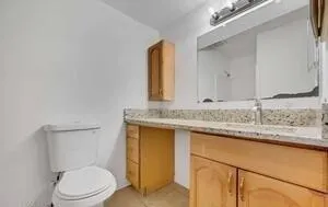 a bathroom with a granite countertop toilet sink and mirror