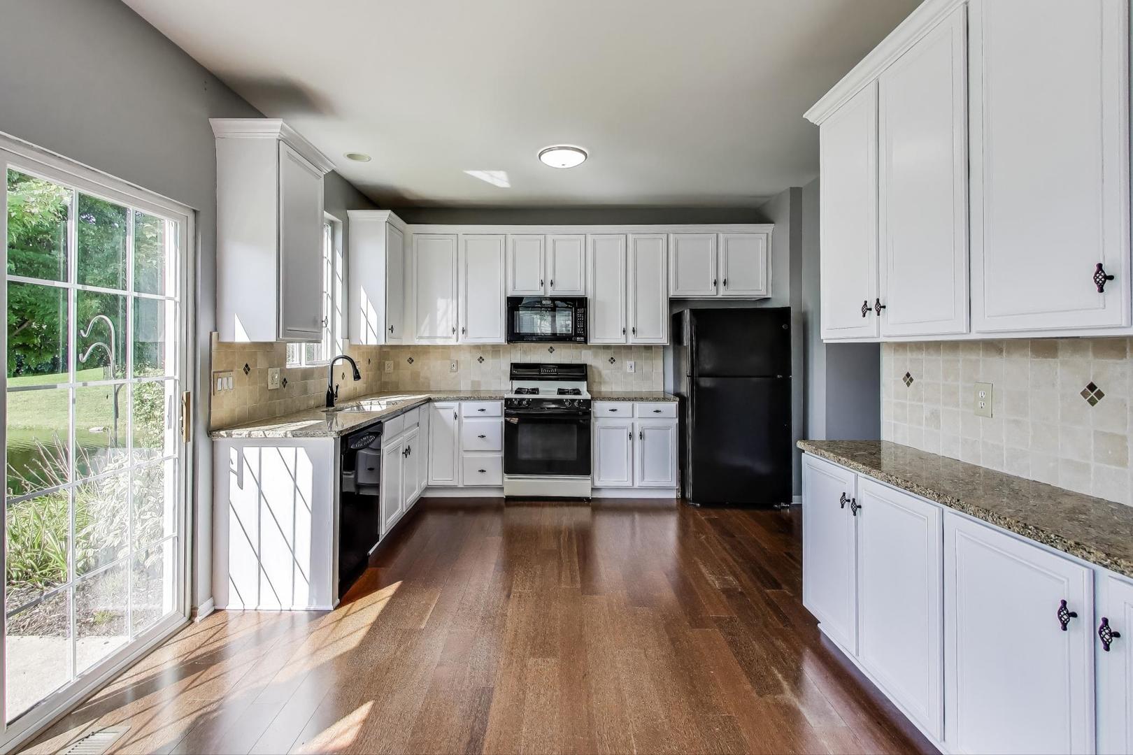 383 Cascade Lane Oswego, IL 60543 - Photo 8 of 35 a kitchen with granite countertop a stove top oven a sink dishwasher a refrigerator and white cabinets with wooden floor