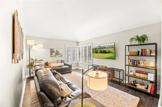 a living room with furniture and a kitchen area with wooden floor