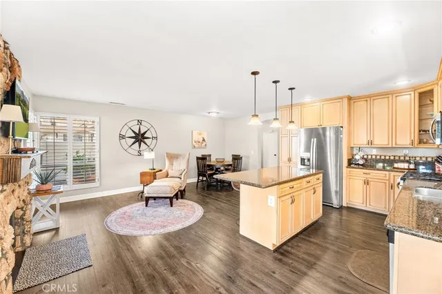 a kitchen with stainless steel appliances kitchen island granite countertop a refrigerator a stove and white cabinets with wooden floor