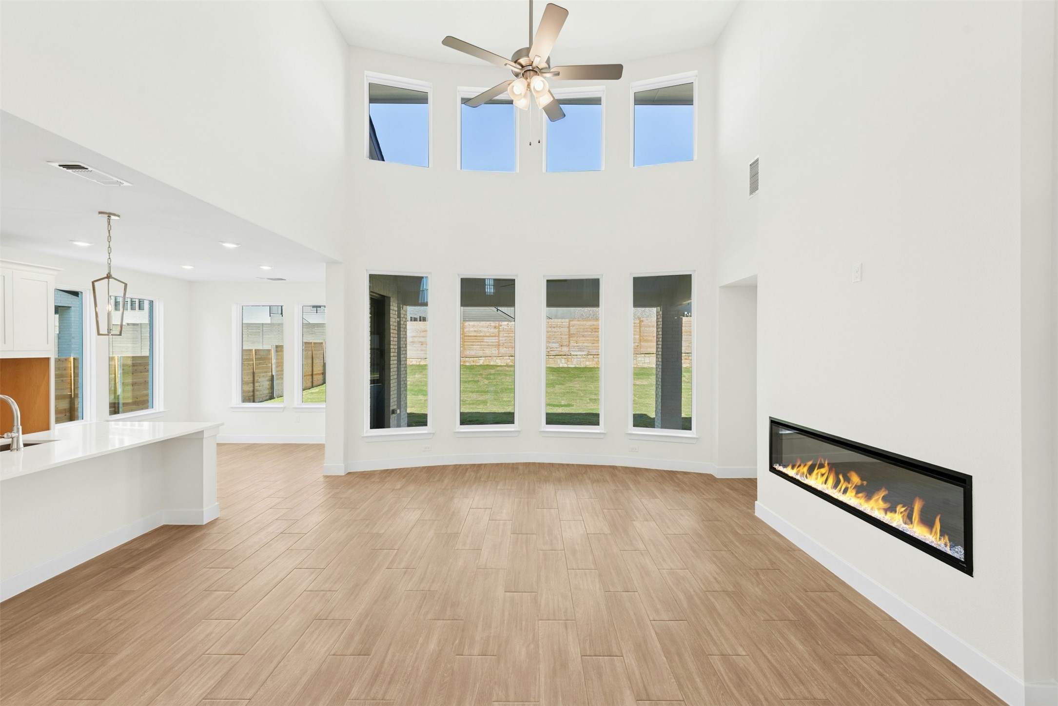 1520 Rodeo Ridge Drive Georgetown, TX 78628 - Photo 2 of 29 Unfurnished living room with a glass covered fireplace, light wood-style floors, plenty of natural light, a high ceiling, and recessed lighting