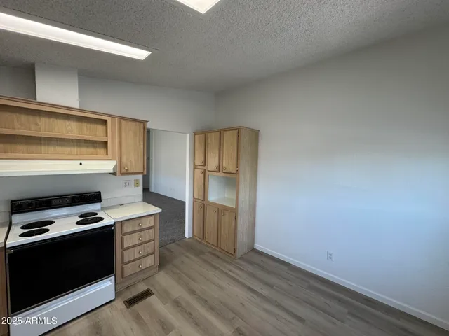 a kitchen with wooden floor and electronic appliances