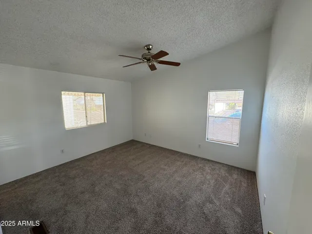 an empty room with windows and fan