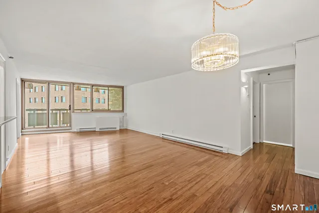 a view of an empty room with wooden floor and fan