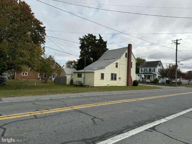 a view of a white house next to a road and yard