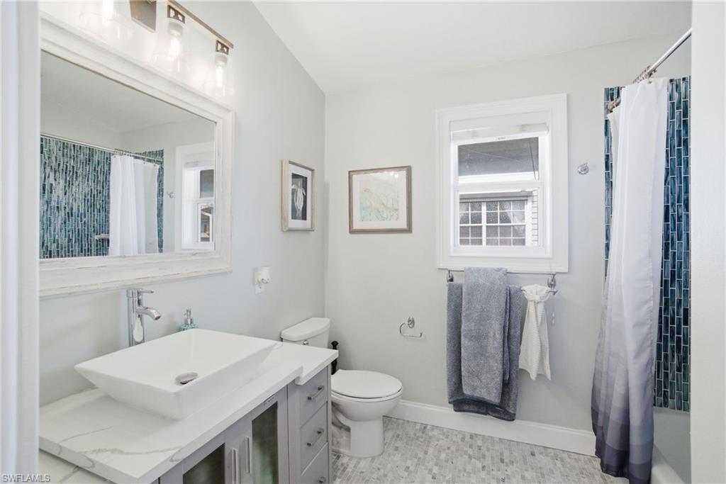 1286 Venetian Way Naples, FL 34110 - Photo 18 of 46 a bathroom with a sink a toilet and a mirror