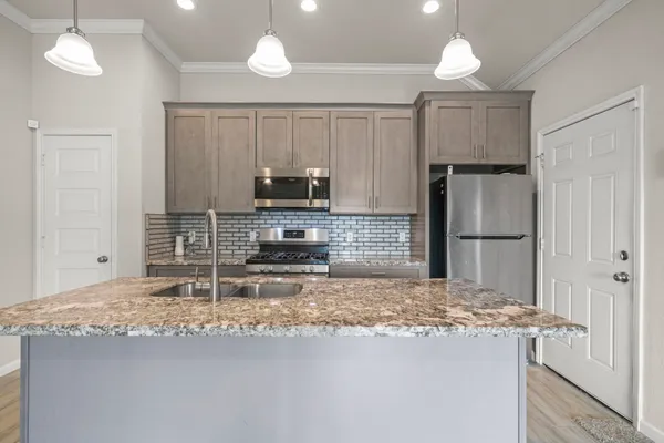 a kitchen with kitchen island granite countertop a stove a refrigerator and a sink