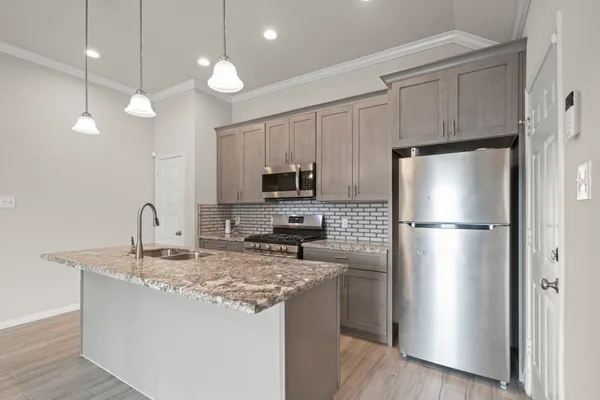 a kitchen with kitchen island a counter space a refrigerator and cabinets