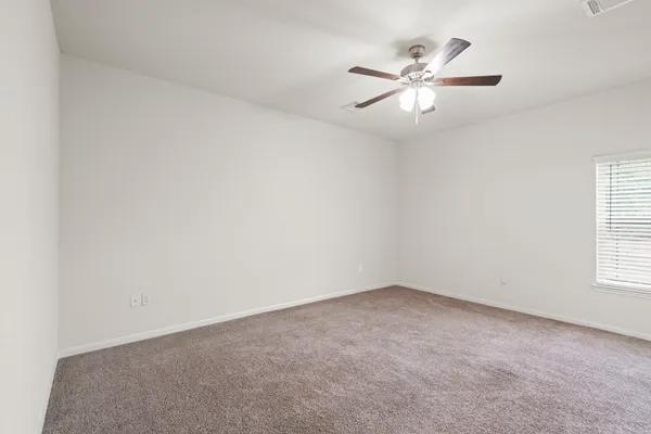 an empty room with windows and fan