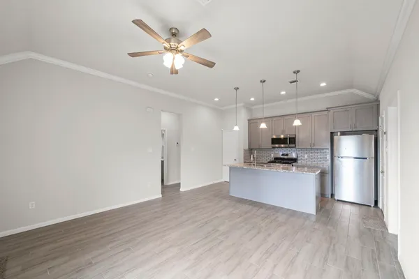a view of kitchen with stainless steel appliances wooden floor and living room view