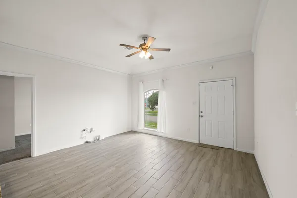a view of a room with wooden floor and a ceiling fan