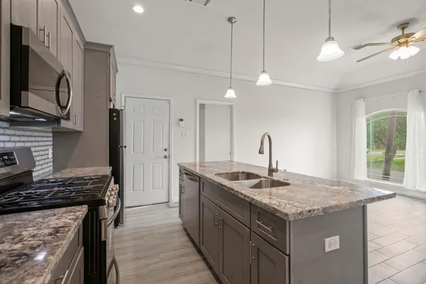 a kitchen with granite countertop kitchen island a sink appliances and a counter top space
