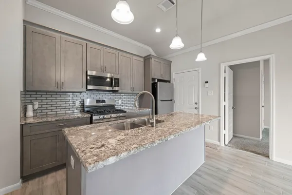 a kitchen with kitchen island granite countertop a sink refrigerator and microwave