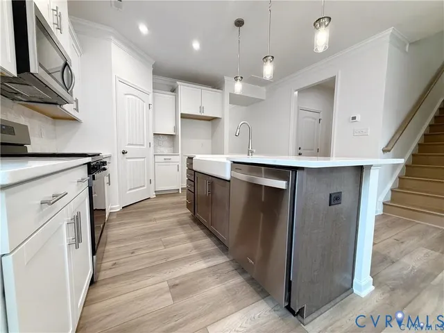 a kitchen with white cabinets appliances and wooden floor
