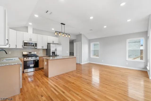 a large kitchen with stainless steel appliances granite countertop a stove a sink dishwasher and a oven with white cabinets