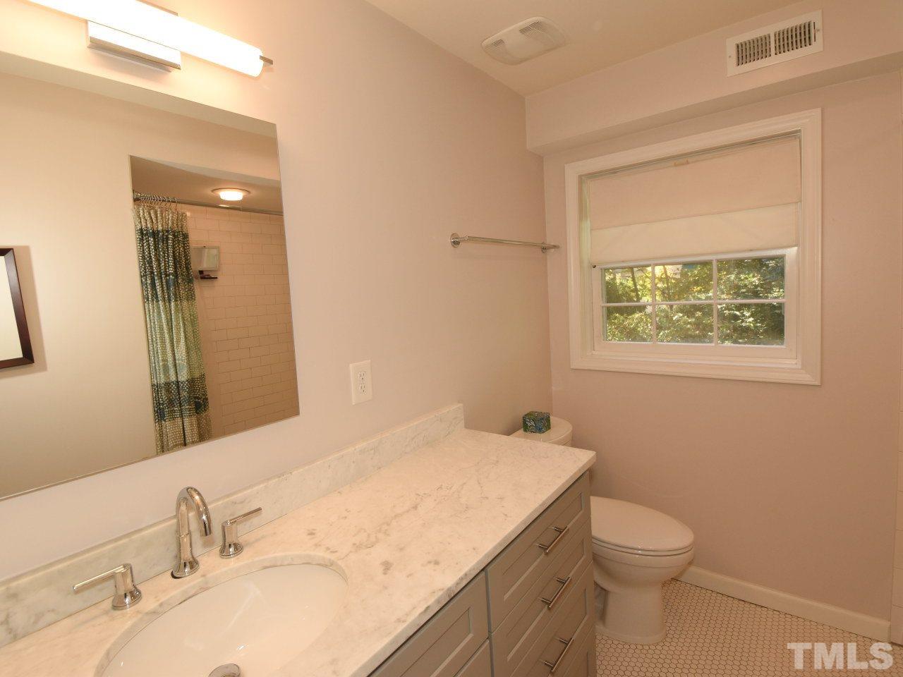 616 Macon Place Raleigh, NC 27609 - Photo 16 of 25 a bathroom with a sink vanity granite toilet and a mirror