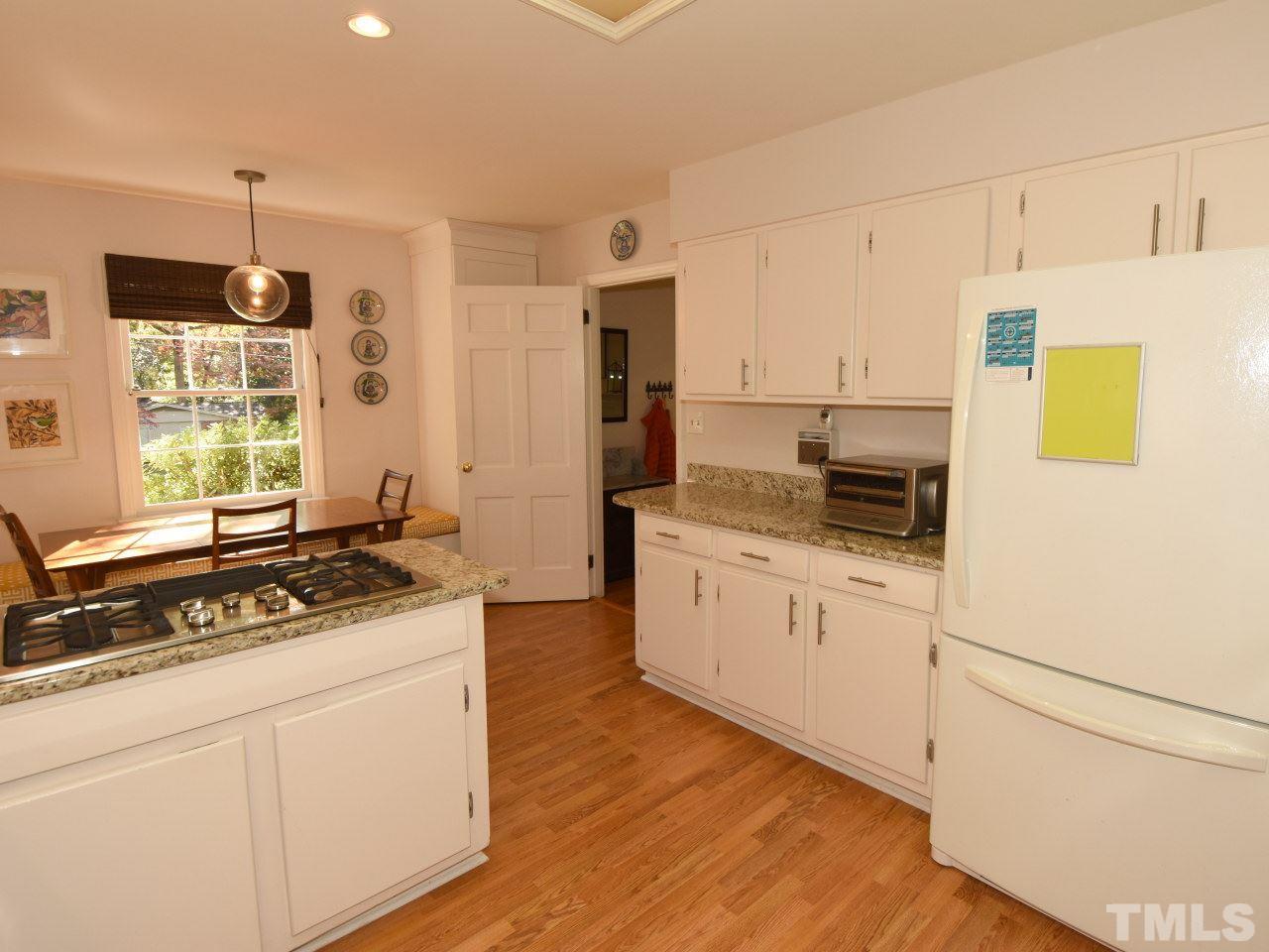 616 Macon Place Raleigh, NC 27609 - Photo 9 of 25 a kitchen with a sink a stove a refrigerator and white cabinets
