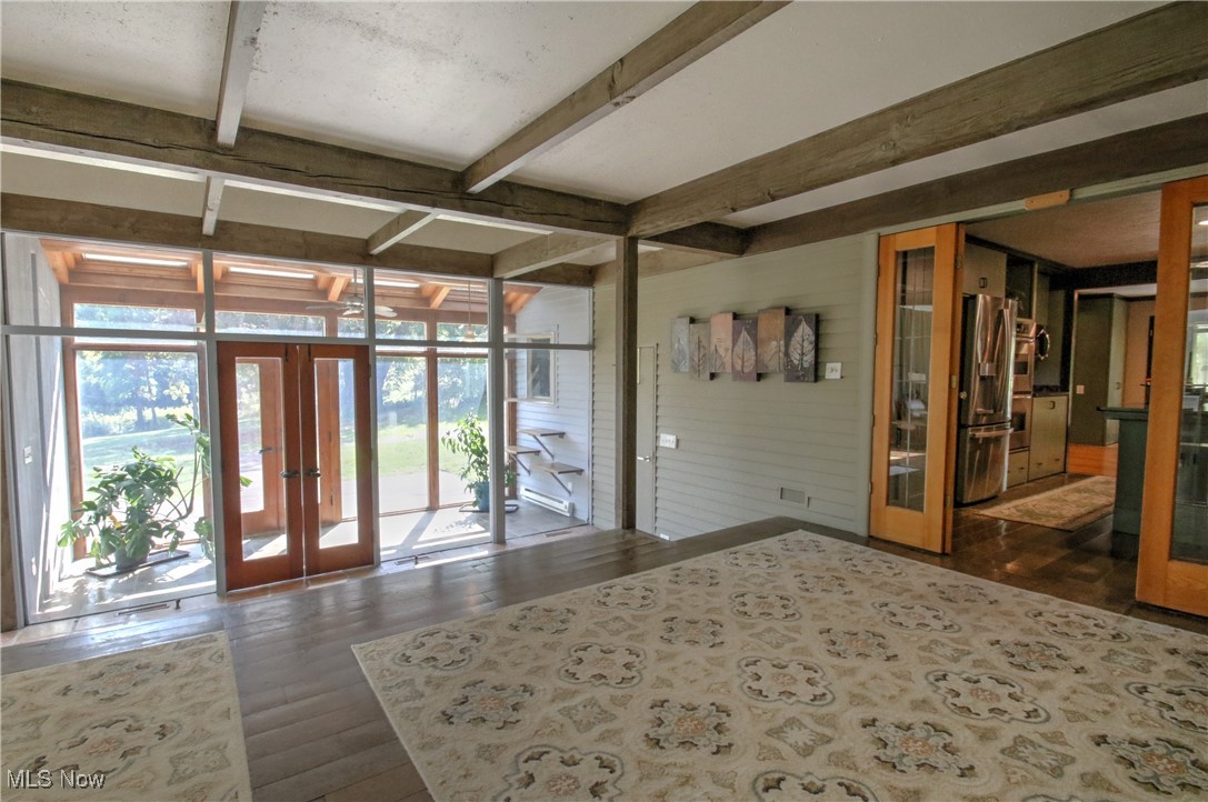 11375 Bean Road Chardon, OH 44024 - Photo 9 of 50 Entrance foyer featuring french doors, dark wood-style flooring, beamed ceiling, wood walls, and a wall of windows