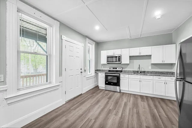 a kitchen with granite countertop a stove top oven sink and cabinets
