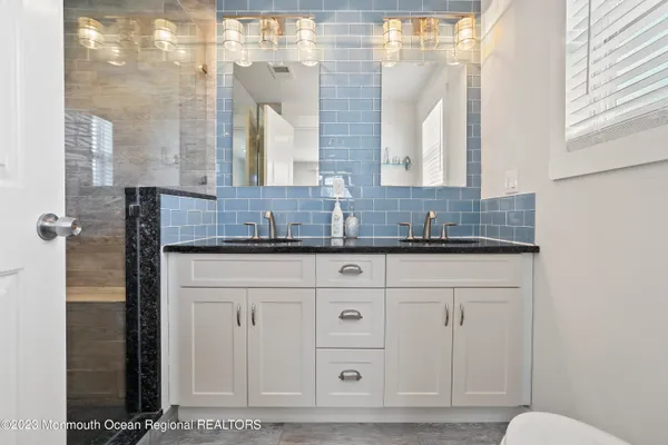 a bathroom with a granite countertop sink a mirror and shower