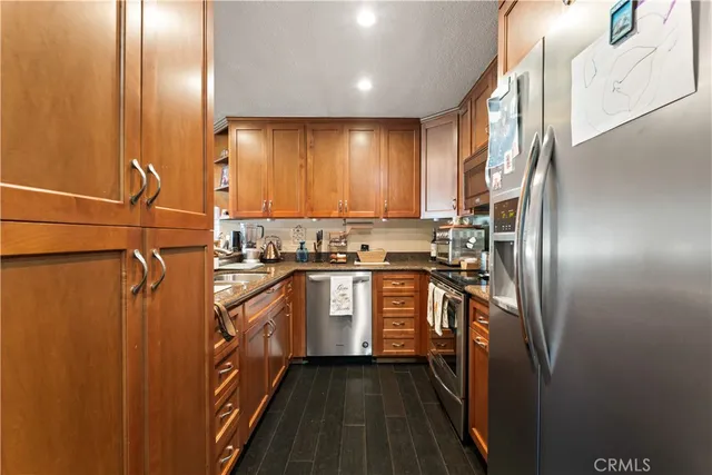 a kitchen with stainless steel appliances granite countertop a refrigerator a sink and wooden cabinets