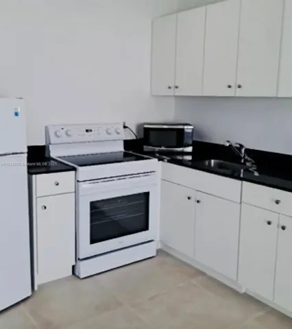 a kitchen with granite countertop white cabinets and stainless steel appliances