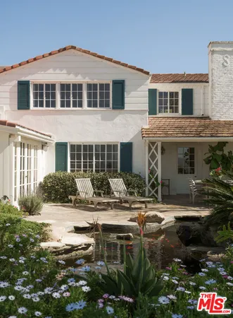 a front view of a house with a garden and sitting area