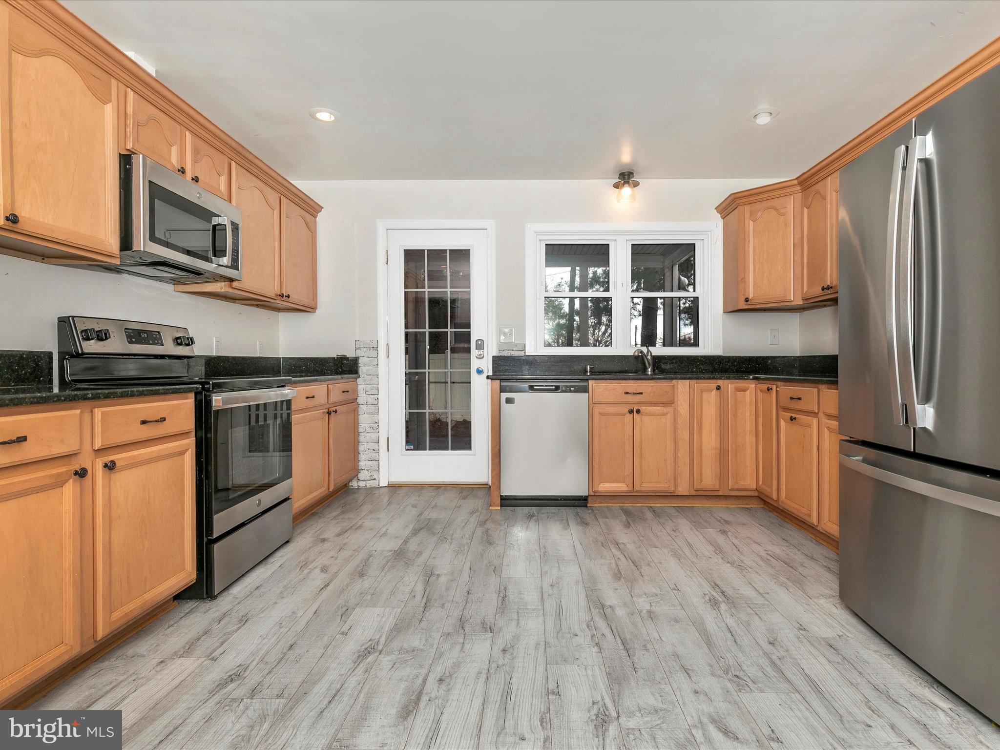8913 Yellow Springs Road Frederick, MD 21702 - Photo 12 of 77 a kitchen with stainless steel appliances granite countertop wooden floors and white cabinets