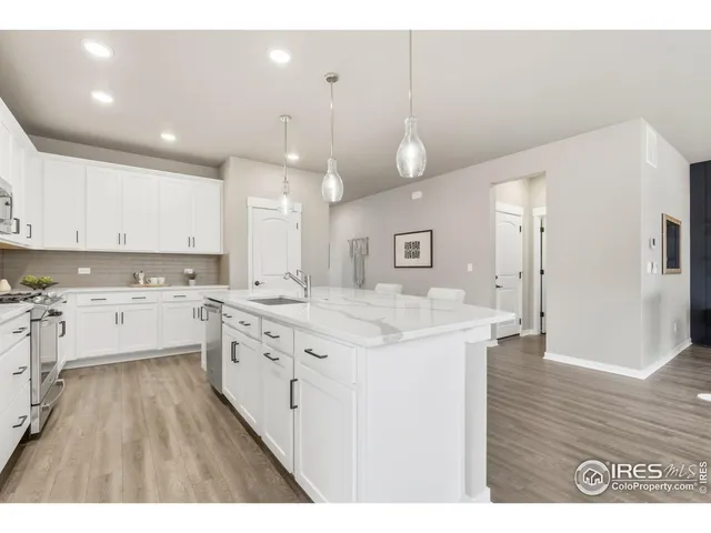 a kitchen with a stove a sink a refrigerator and white cabinets with wooden floor