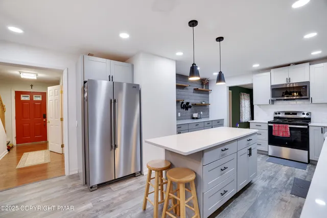 a kitchen with stainless steel appliances kitchen island granite countertop a refrigerator a oven a sink and a wooden cabinets