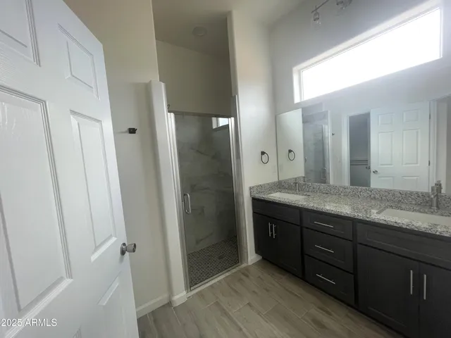 a bathroom with a granite countertop sink a mirror and a shower